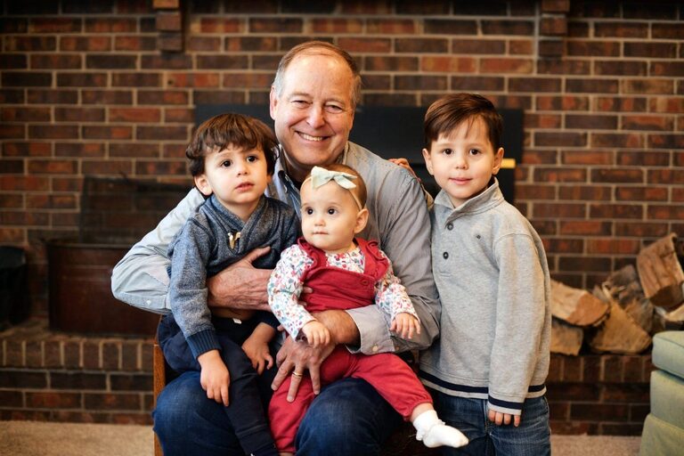 Gex Williams with three young children by a brick fireplace